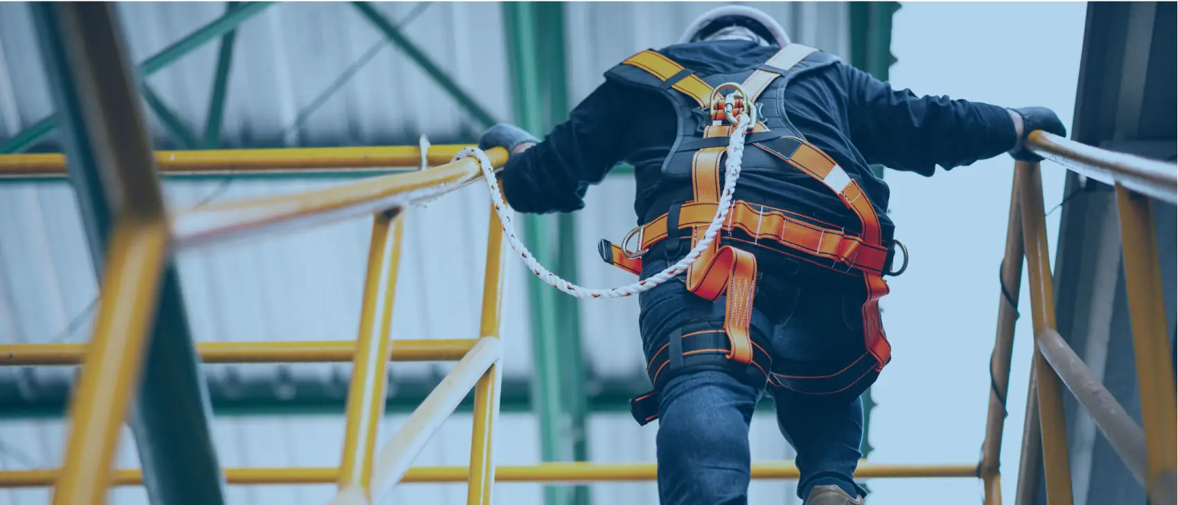 Worker wearing a safety harness walking up stairs