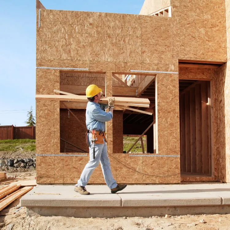 Construction worker carrying lumber at a new home build.